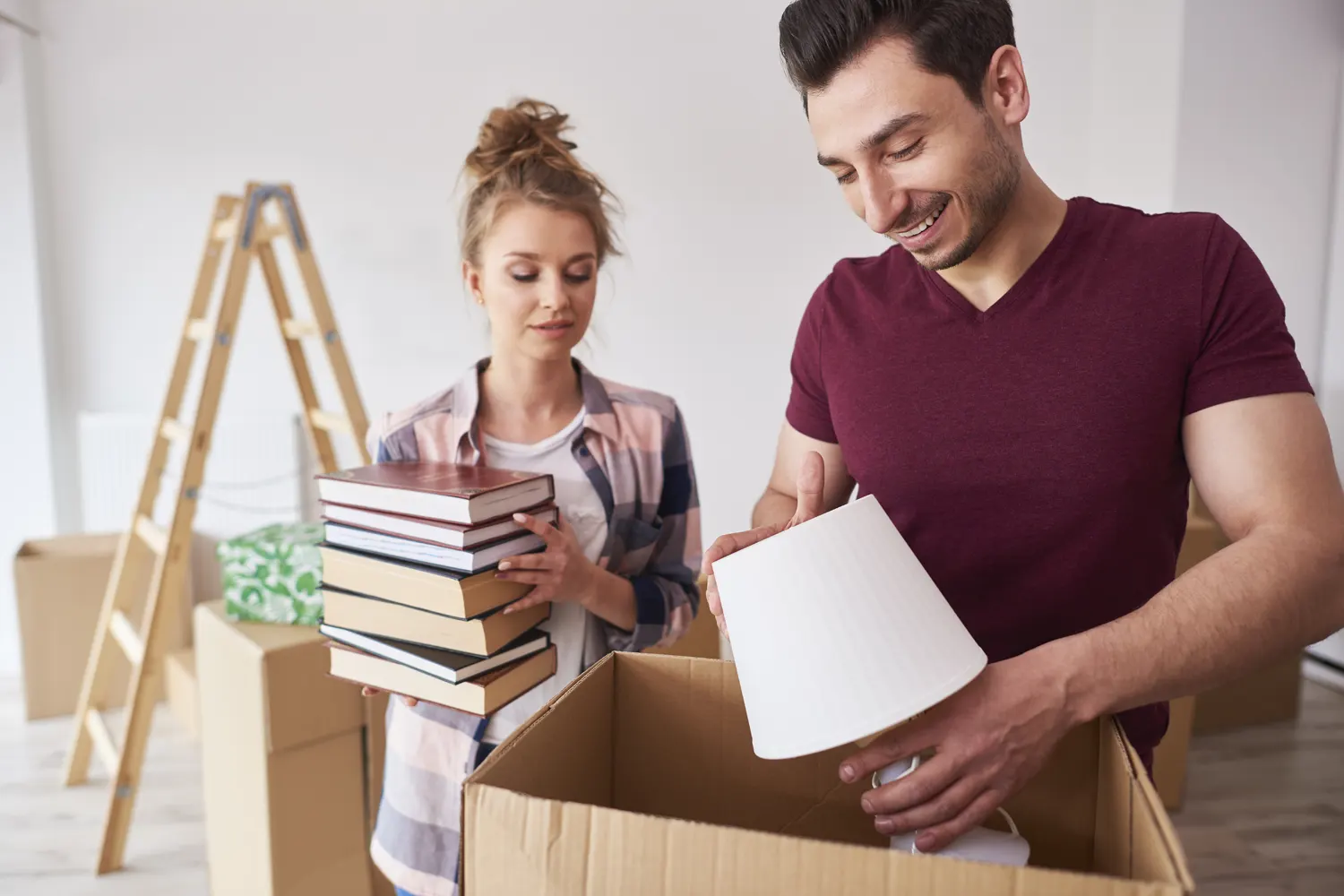 A couple packing books into moving boxes
