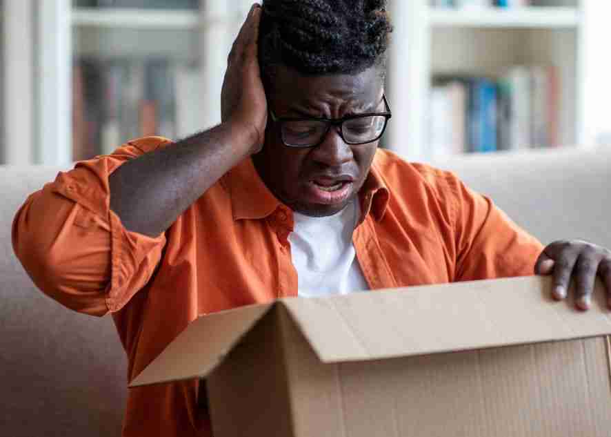 a distraught man looking at broken items in a box
