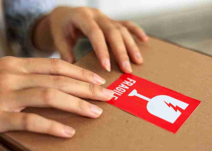 a fragile label sticker being added to a box