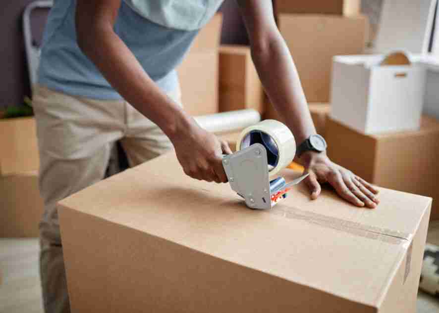 a person sealing a moving box with tape