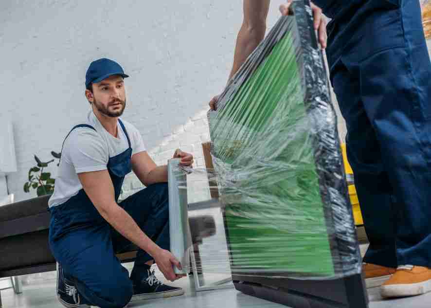 movers wrapping a tv for moving