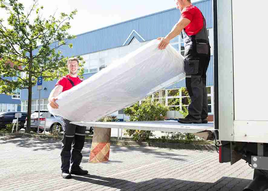 two movers carrying a mattress out of a truck