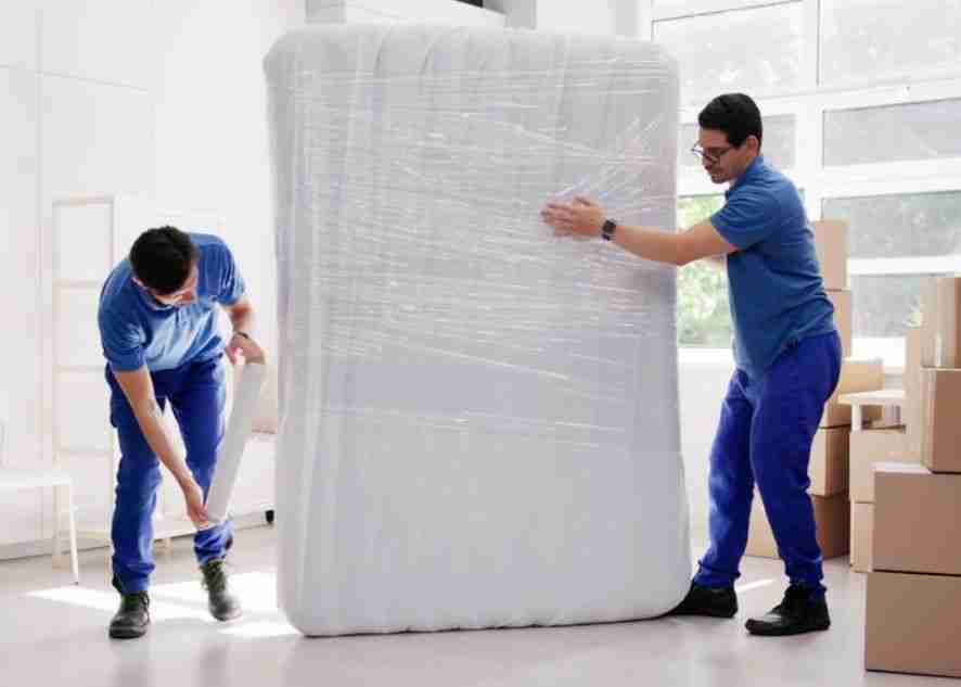 two movers wrapping a mattress