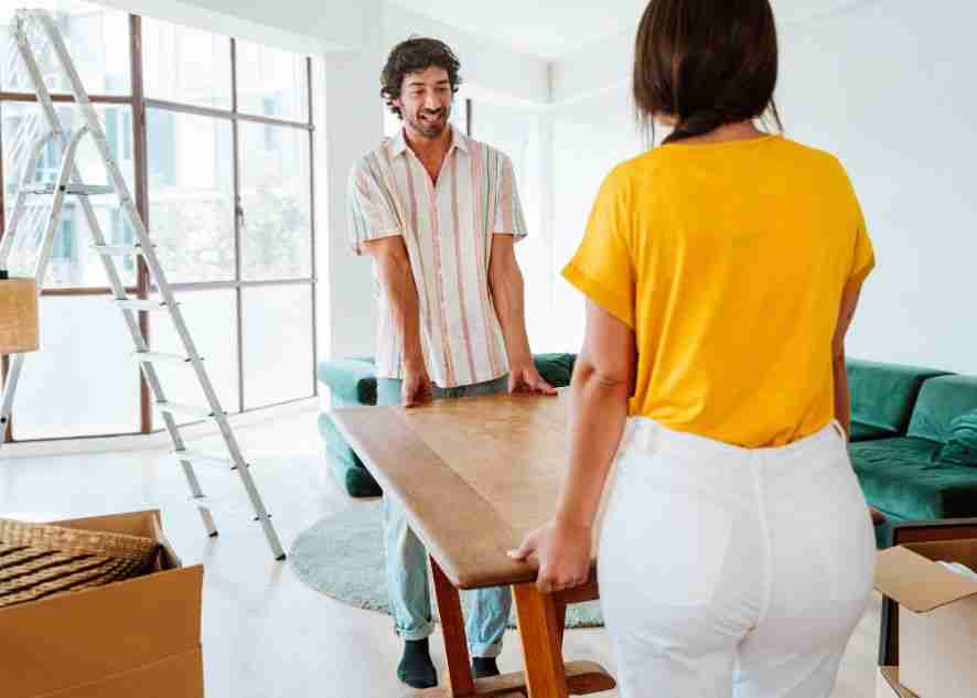 two people moving a table into an apartment